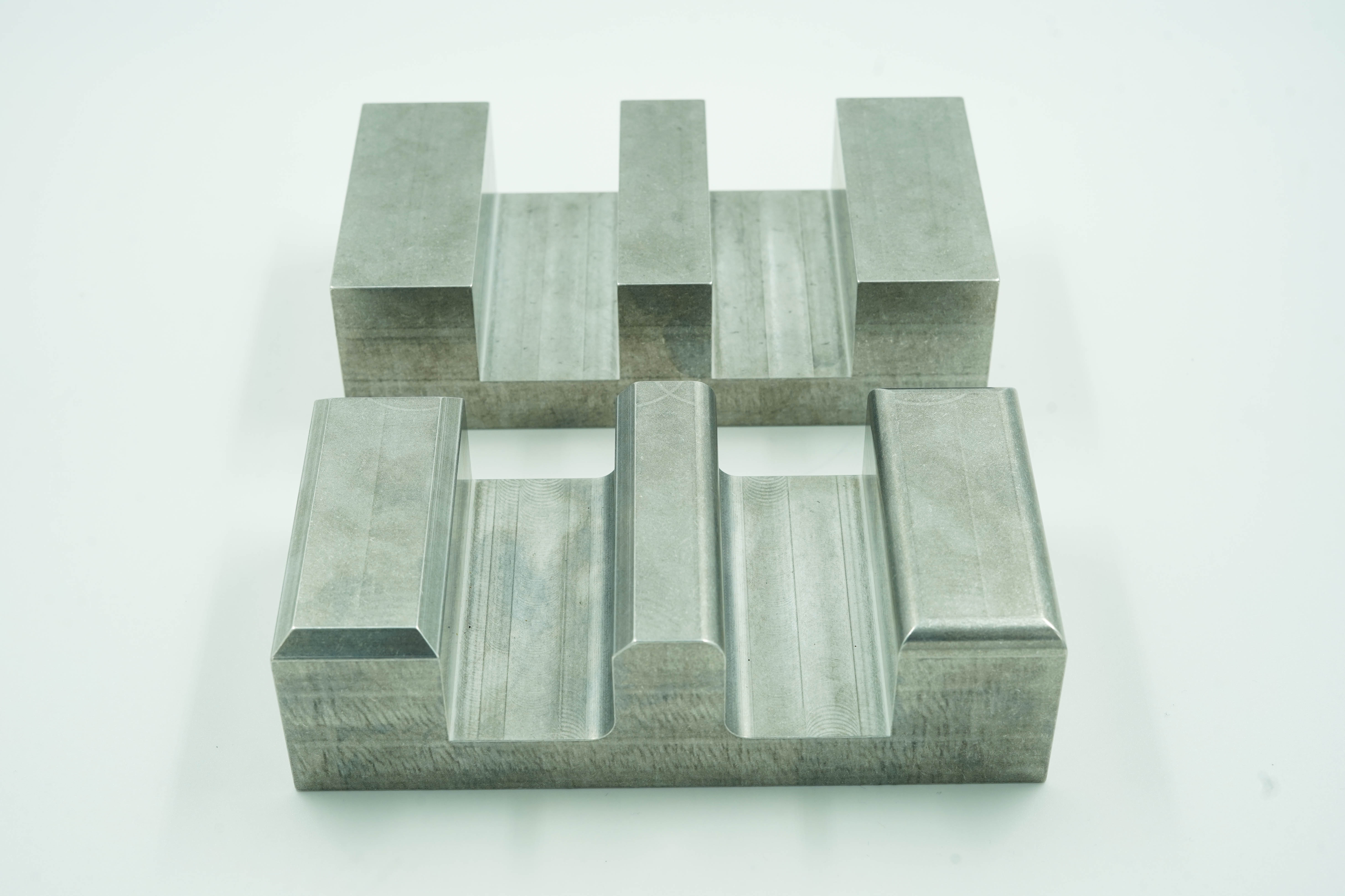 Two machined parts - one without chamfers and fillets, and another with chamfers and fillets